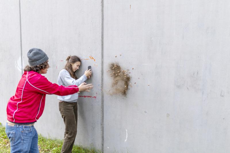 Voor een schoolproject gooit een jongen stenen tegen een muur terwijl een andere leerling van Kunstkaai dit filmt.